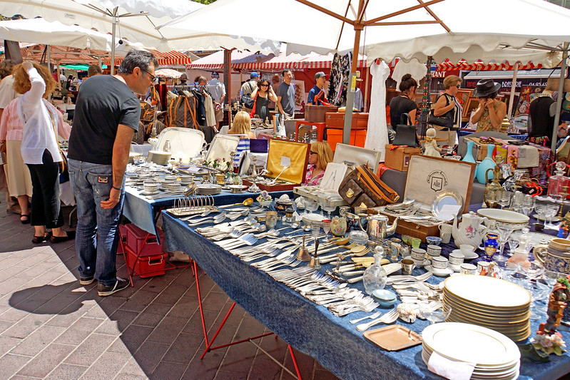 Outdoor market tables laid with antique flatware and dishes.