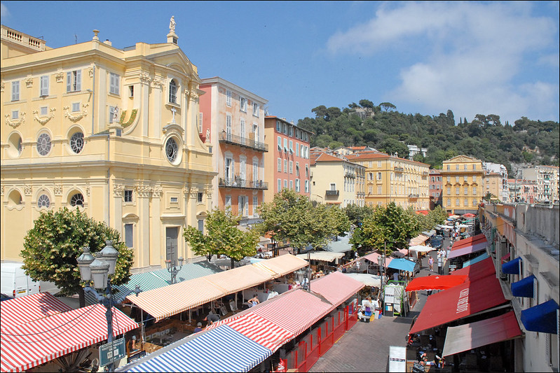 Le Marché du Cours Saleya in Nice with striped covered market stalls and colorful surrounding buildings.