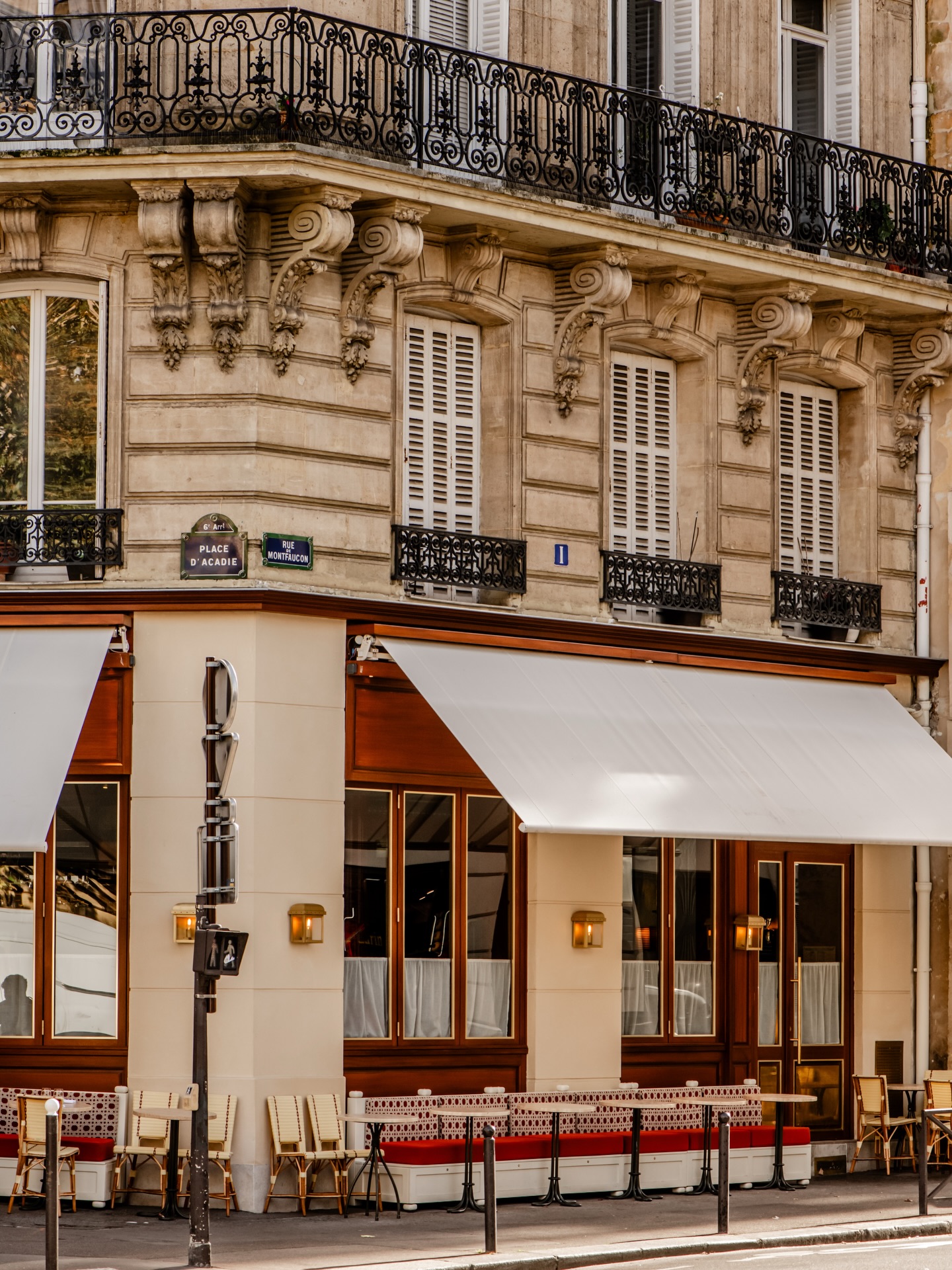 Brass restaurant exterior in Paris with a shaded terrace and intimate bistro dining tables.