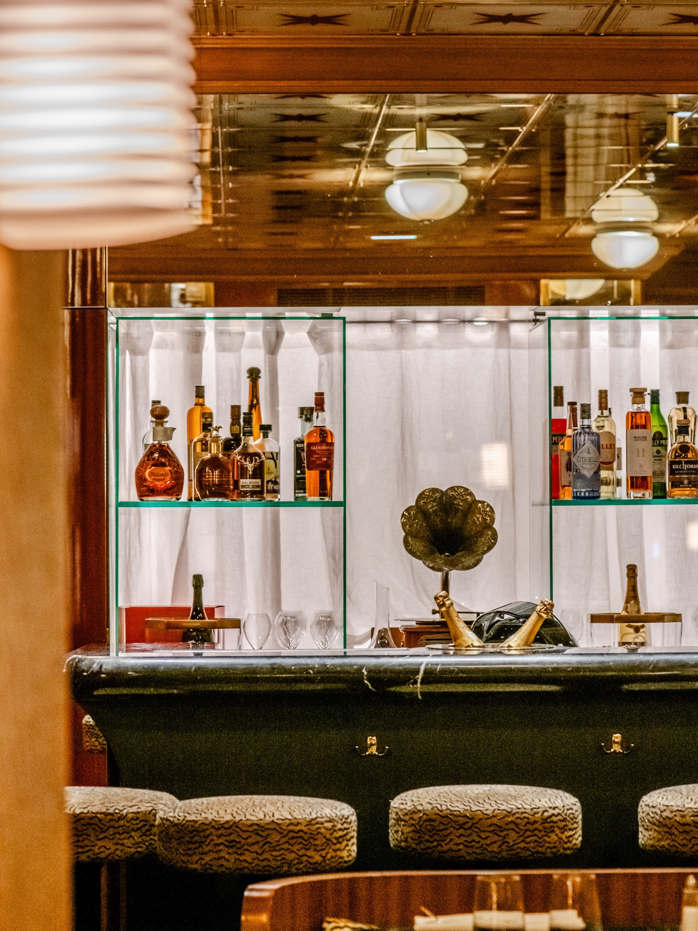 Brass restaurant interior in Paris, featuring an art deco metal ceiling, a marble bar, and leopard print upholstered stools.