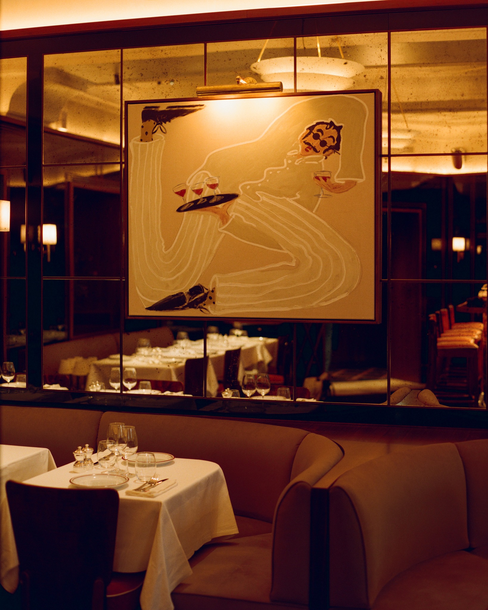 Cherry restaurant interior in Paris, featuring intimate dinning tables and booths, original art, and mirrored walls.
