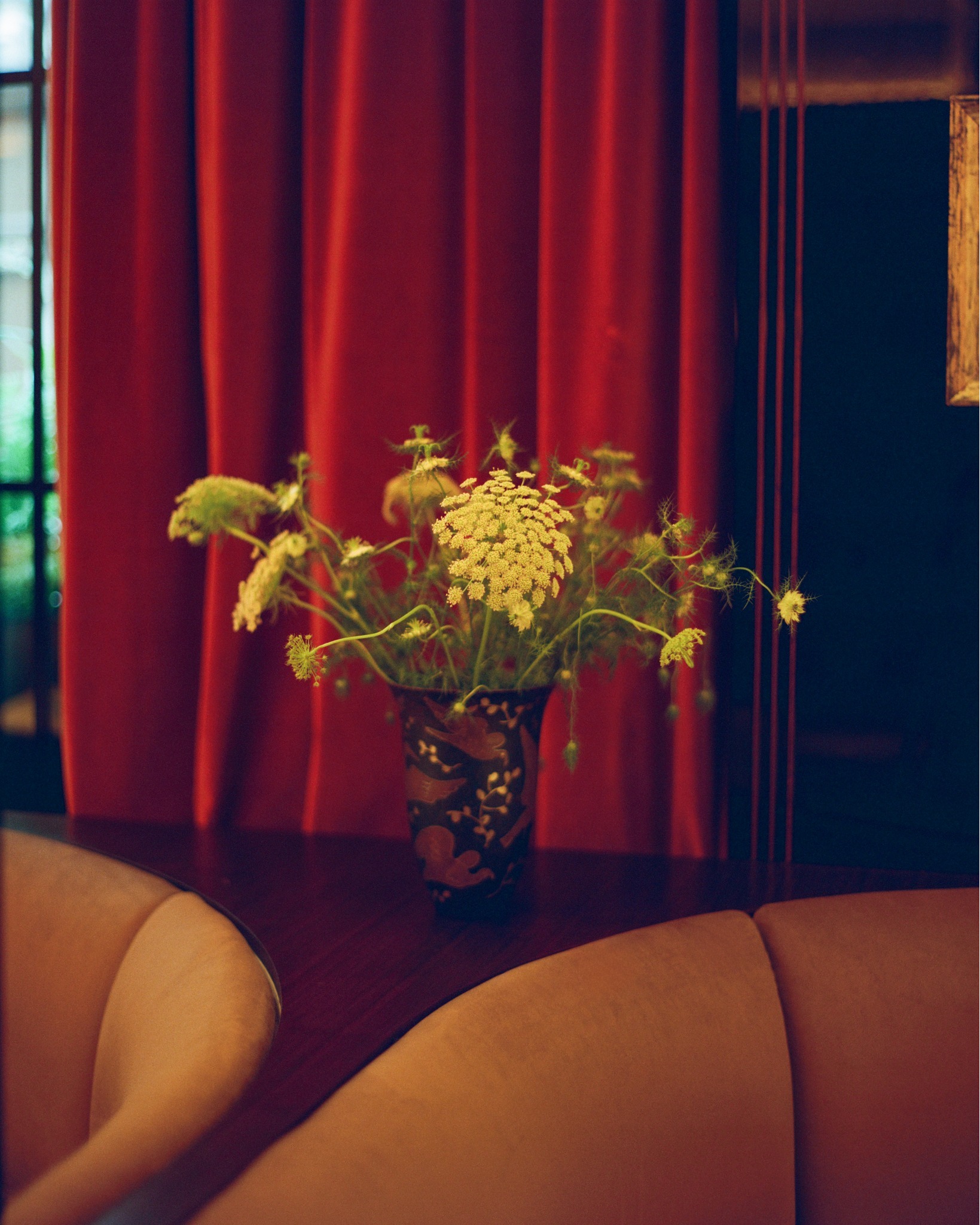Cherry restaurant interior in Paris, featuring freshly cut flowers between two booths, and moody lighting.