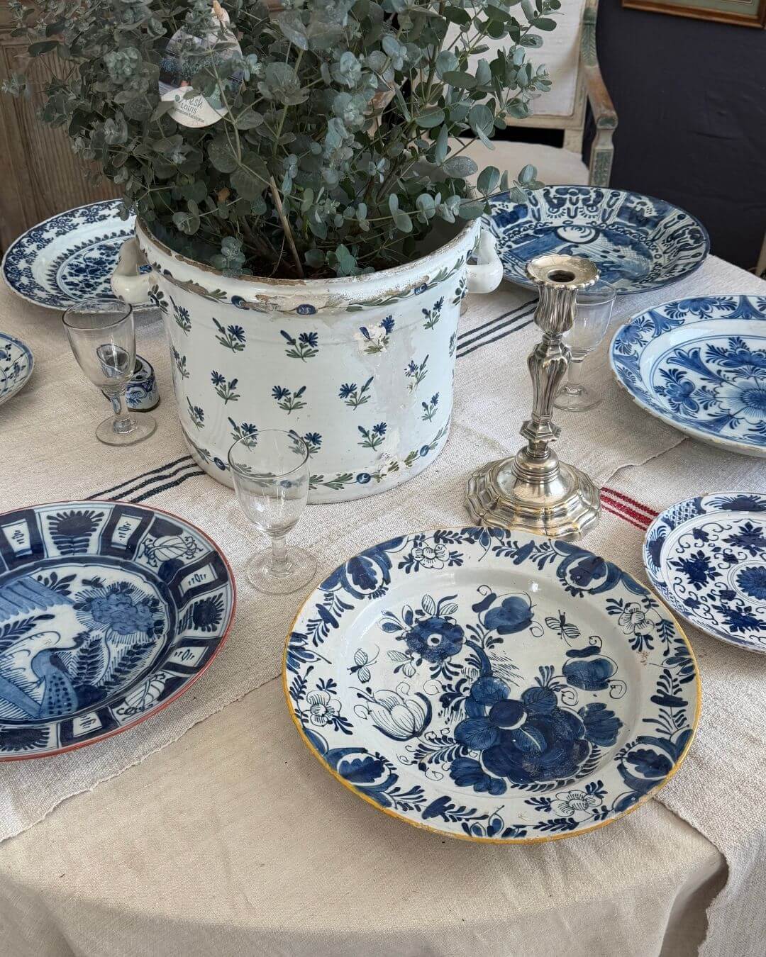 Blue and white china laid on a table set with vintage French linens.