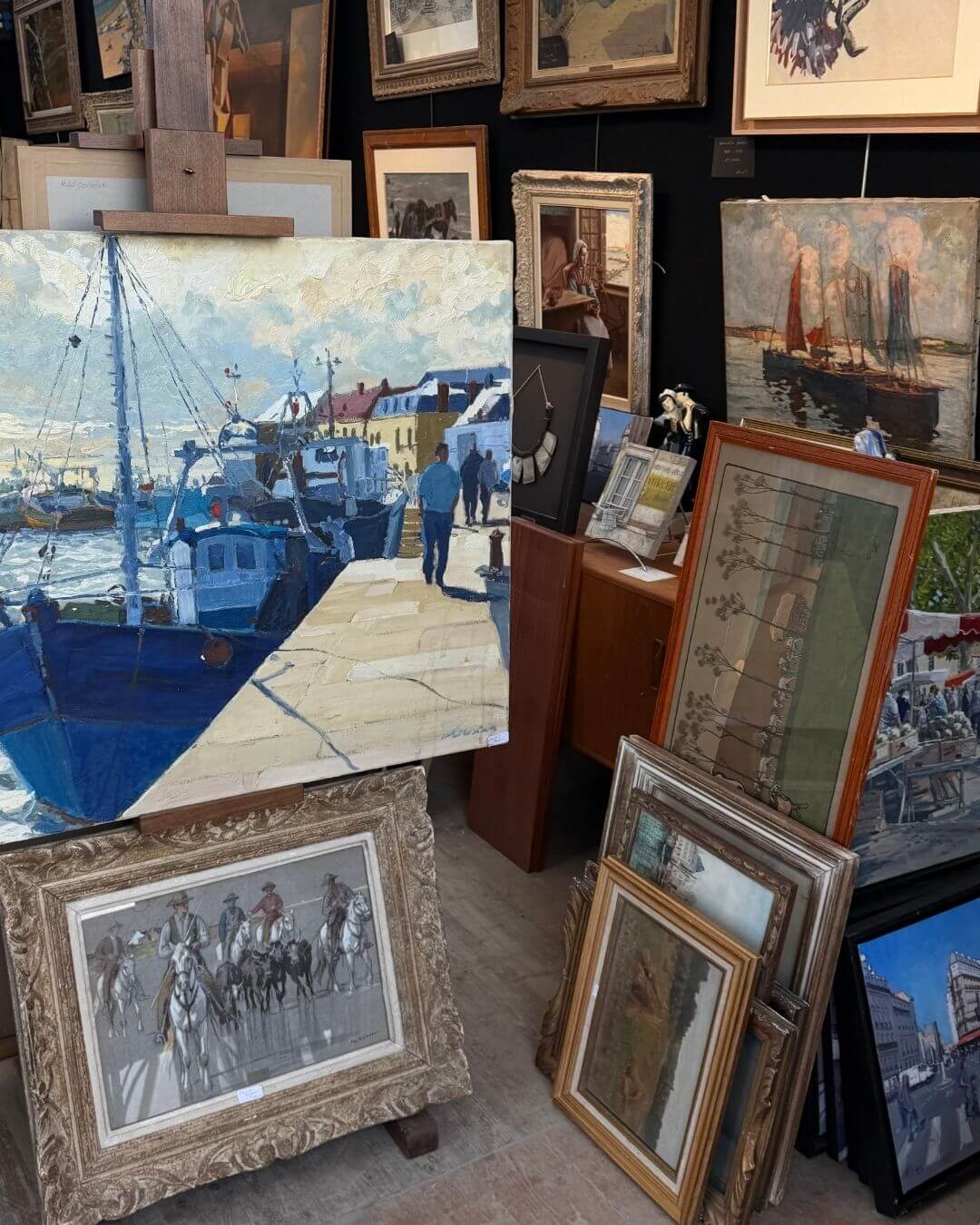 Parisian antique market stall featuring a collection of vintage and antique paintings.