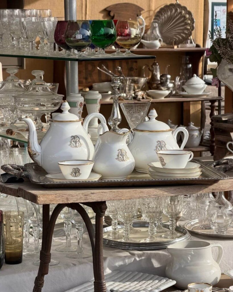 French antique market featuring tables of vintage glass and china sets.