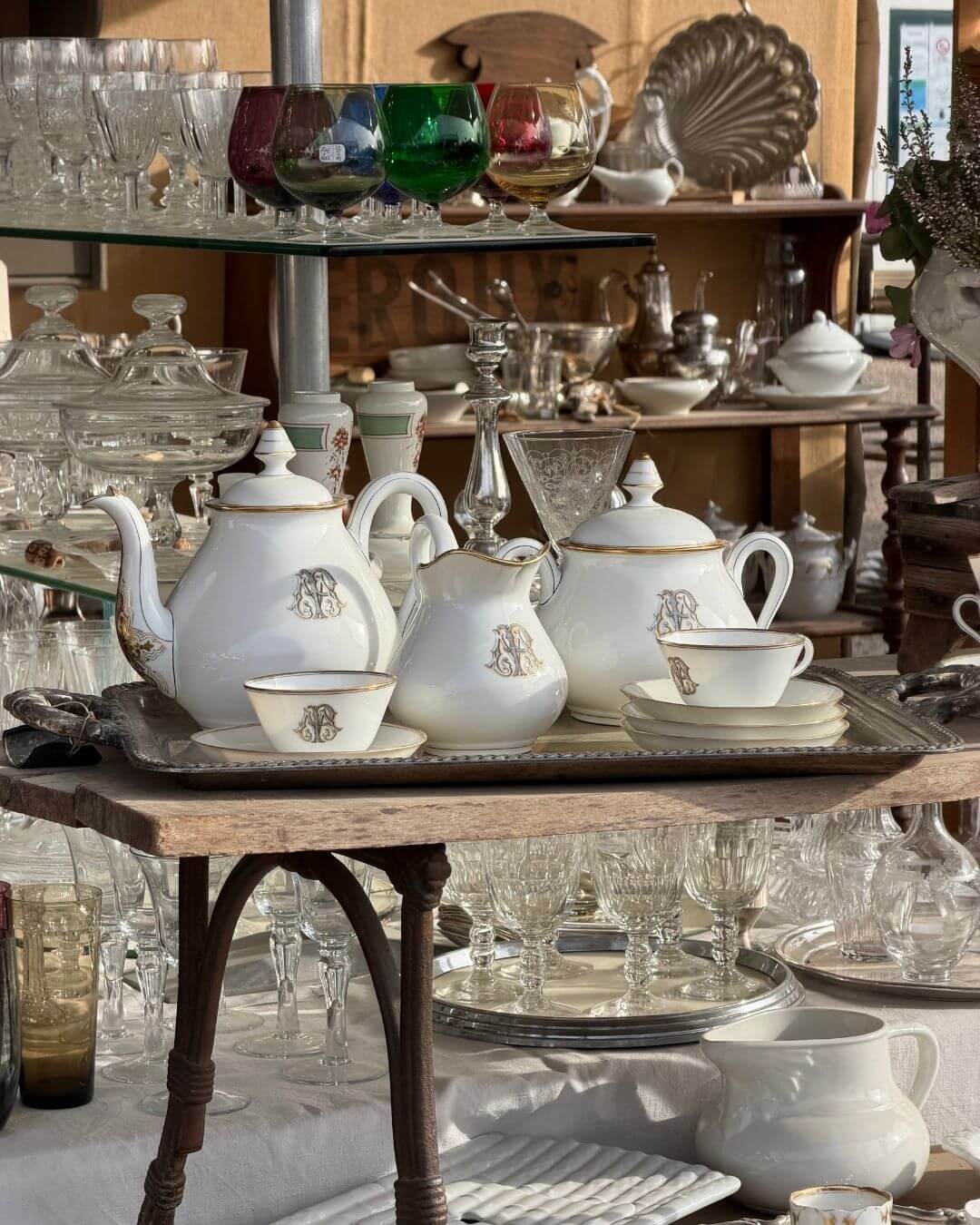 French antique market featuring tables of vintage glass and china sets.