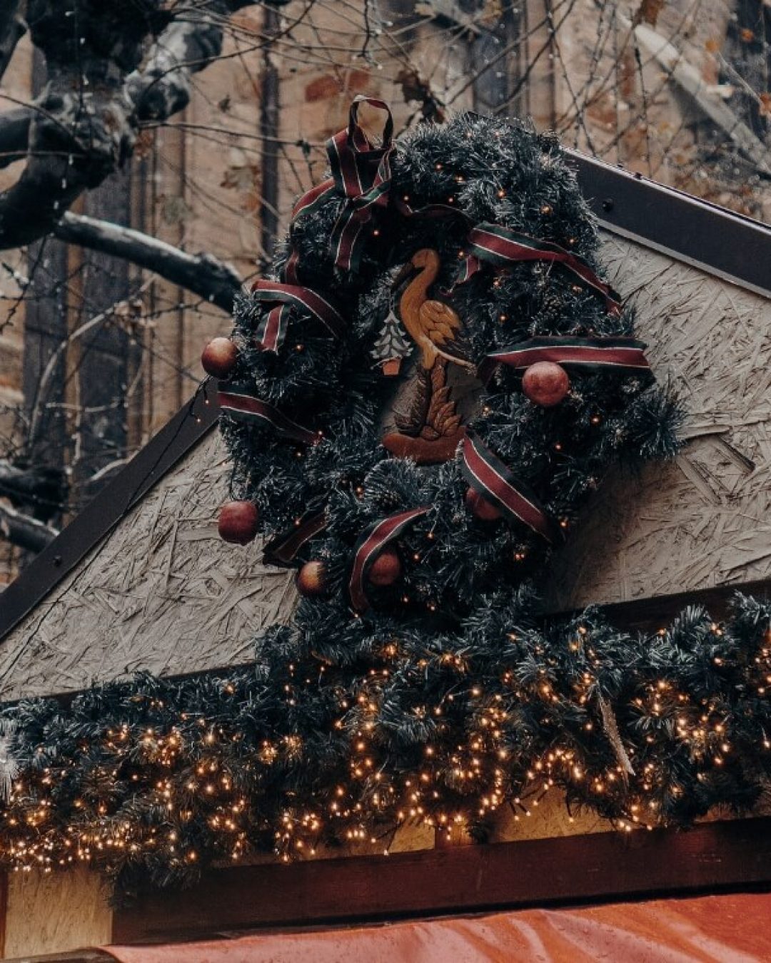 Holiday wreath mounted at a Christmas market in Reims, France with holiday garland below.