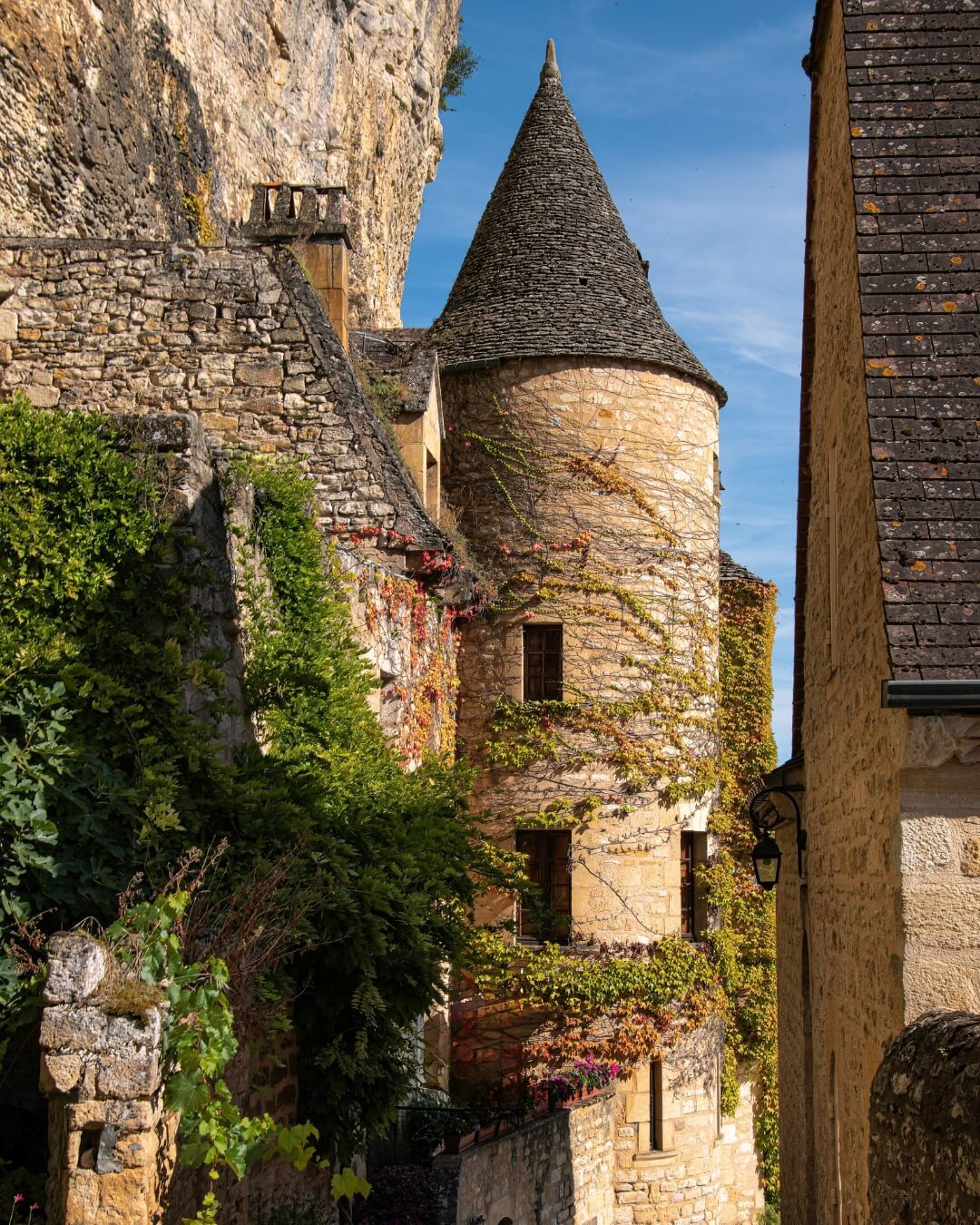 Village street and historic chapel covered in climbing ivy in Dordogne, France.