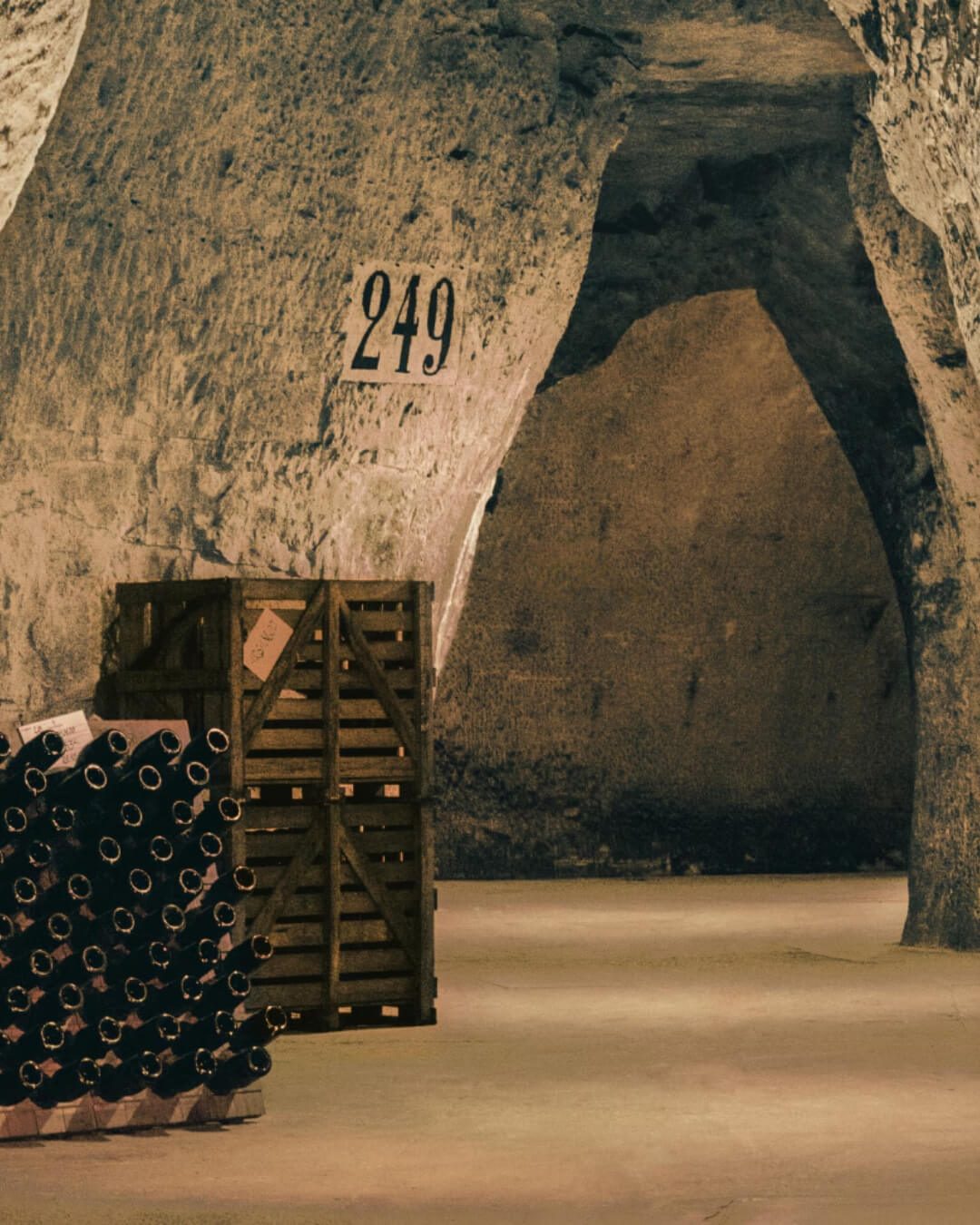 Historic stone champagne cellar in France, with wooden crates along the wall.