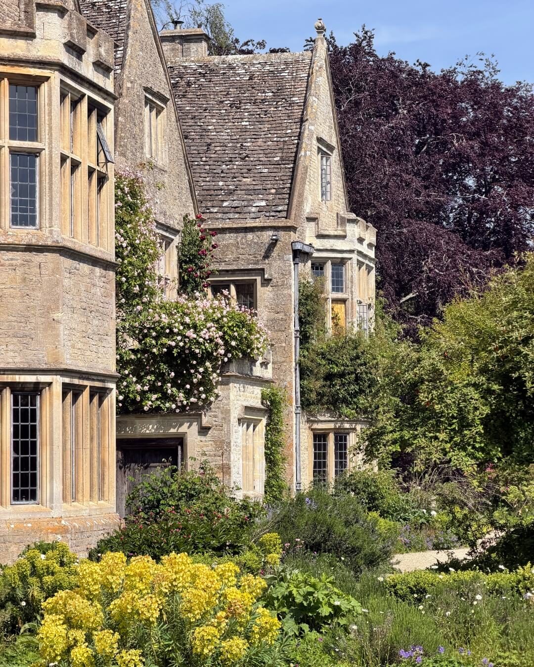 Asthall Manor and garden in the English Cotswolds featuring the historic estate and lush greenery.