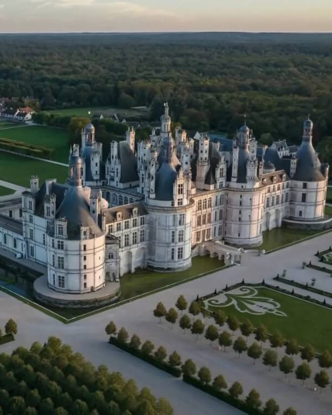 View of Chambord Castle, with manicured traditional French gardens spanning the estate.