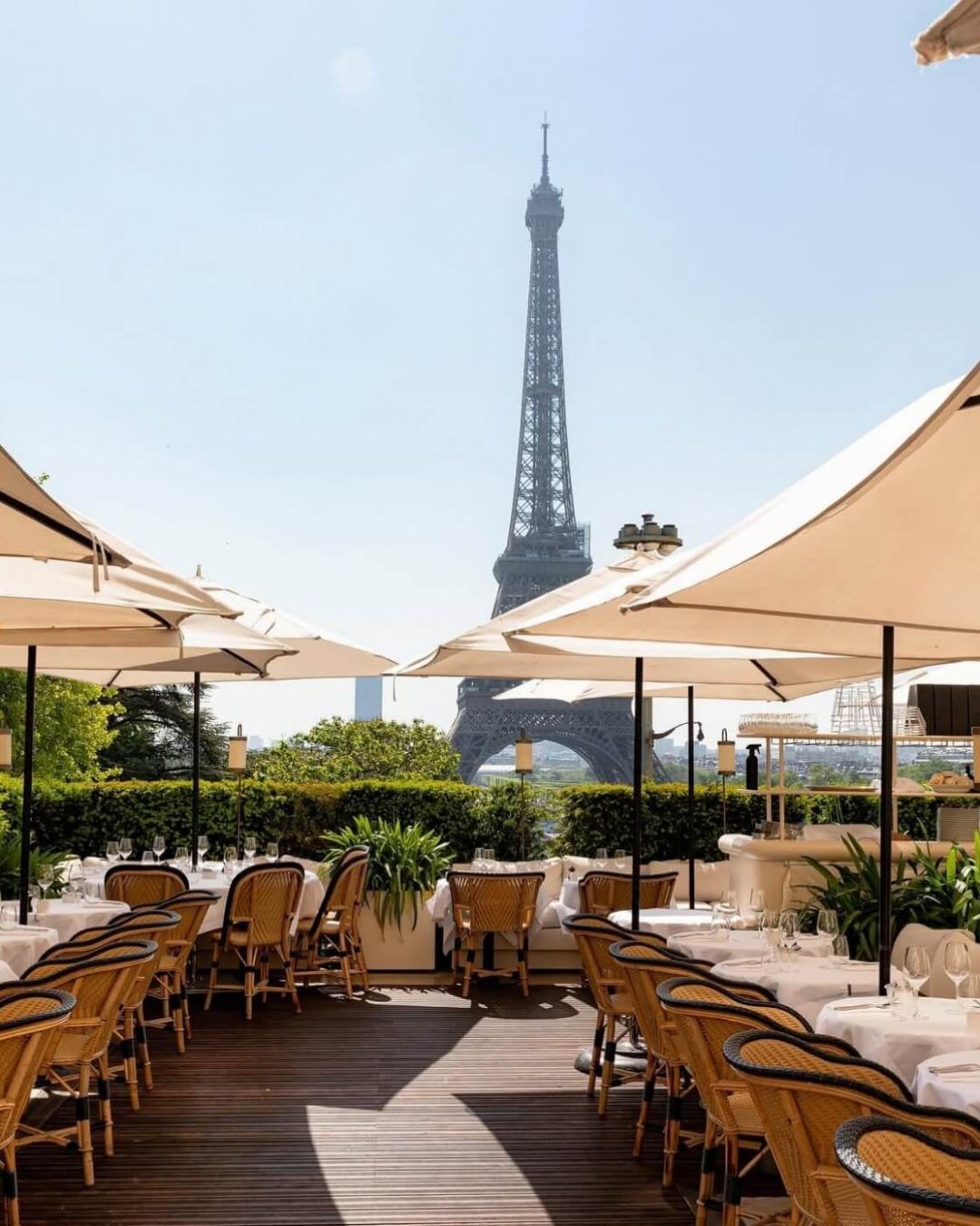 A Parisian rooftop restaurant overlooking the Eiffel Tower's facade.