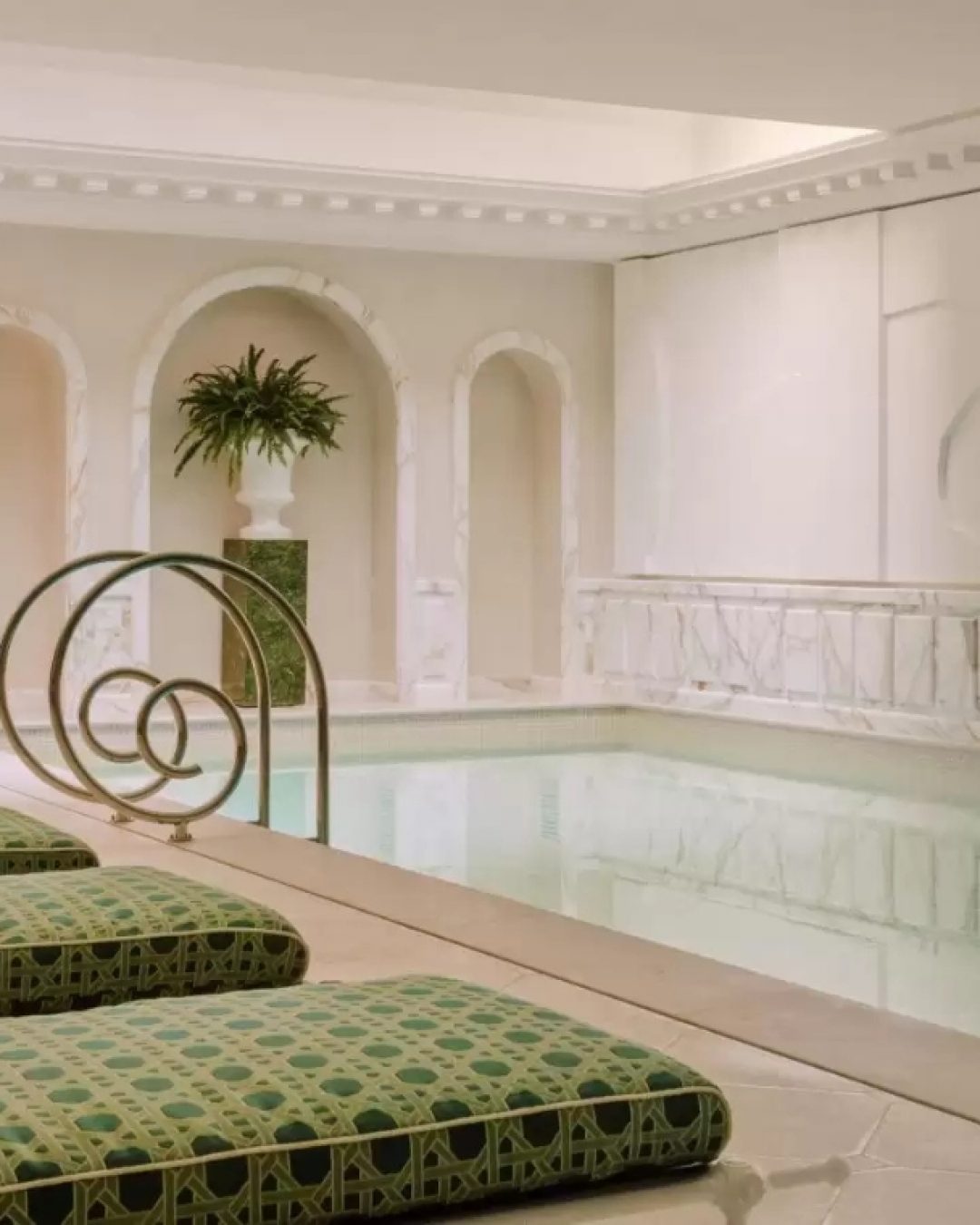 Luxury indoor pool with marble walls and green chaises at Saint James Hotel & Spa in Paris.