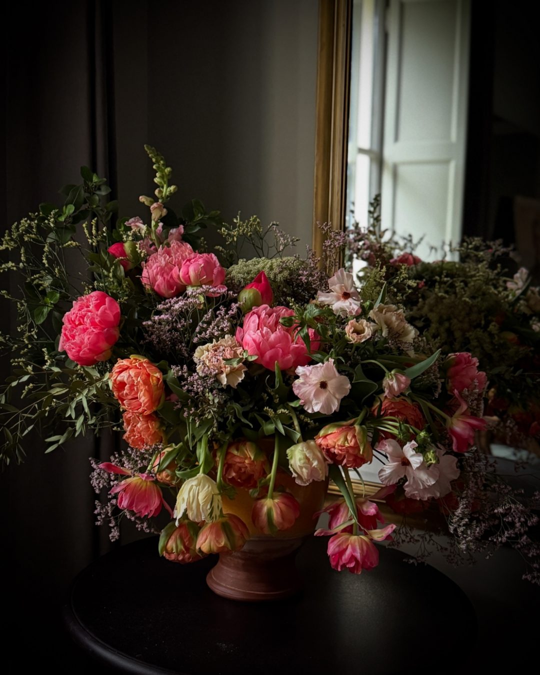 Bouquet of freshly bloomed pink and orange flowers leaning and reaching toward the light.