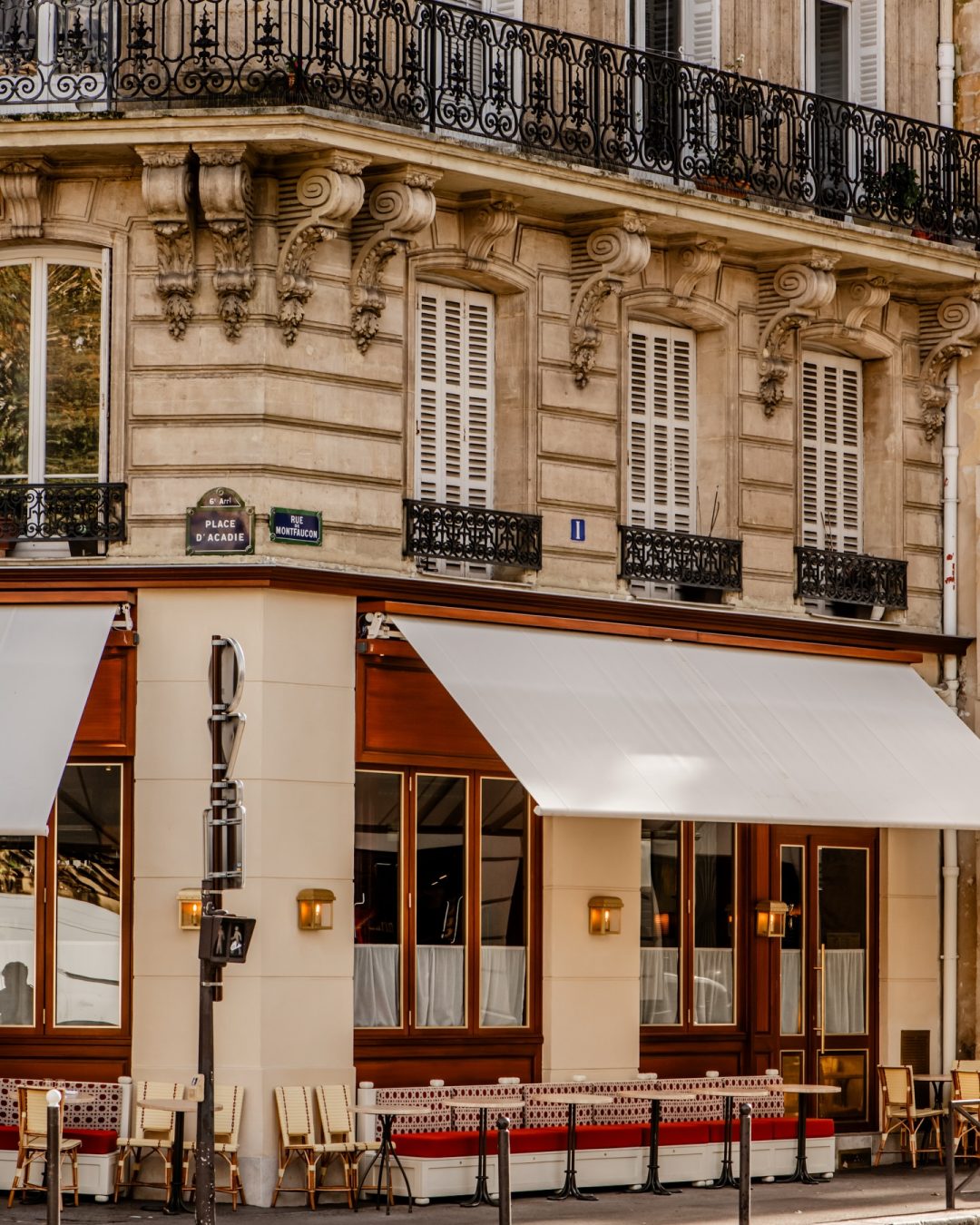 Brass restaurant exterior in Paris with a shaded terrace and intimate bistro dining tables.