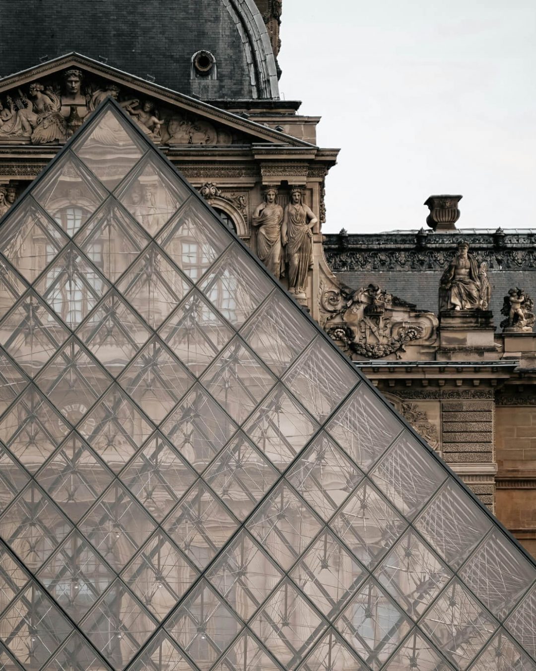 View of the historic Louvre Museum facade framed by the iconic I.M. Pei glass pyramid in Paris, France.