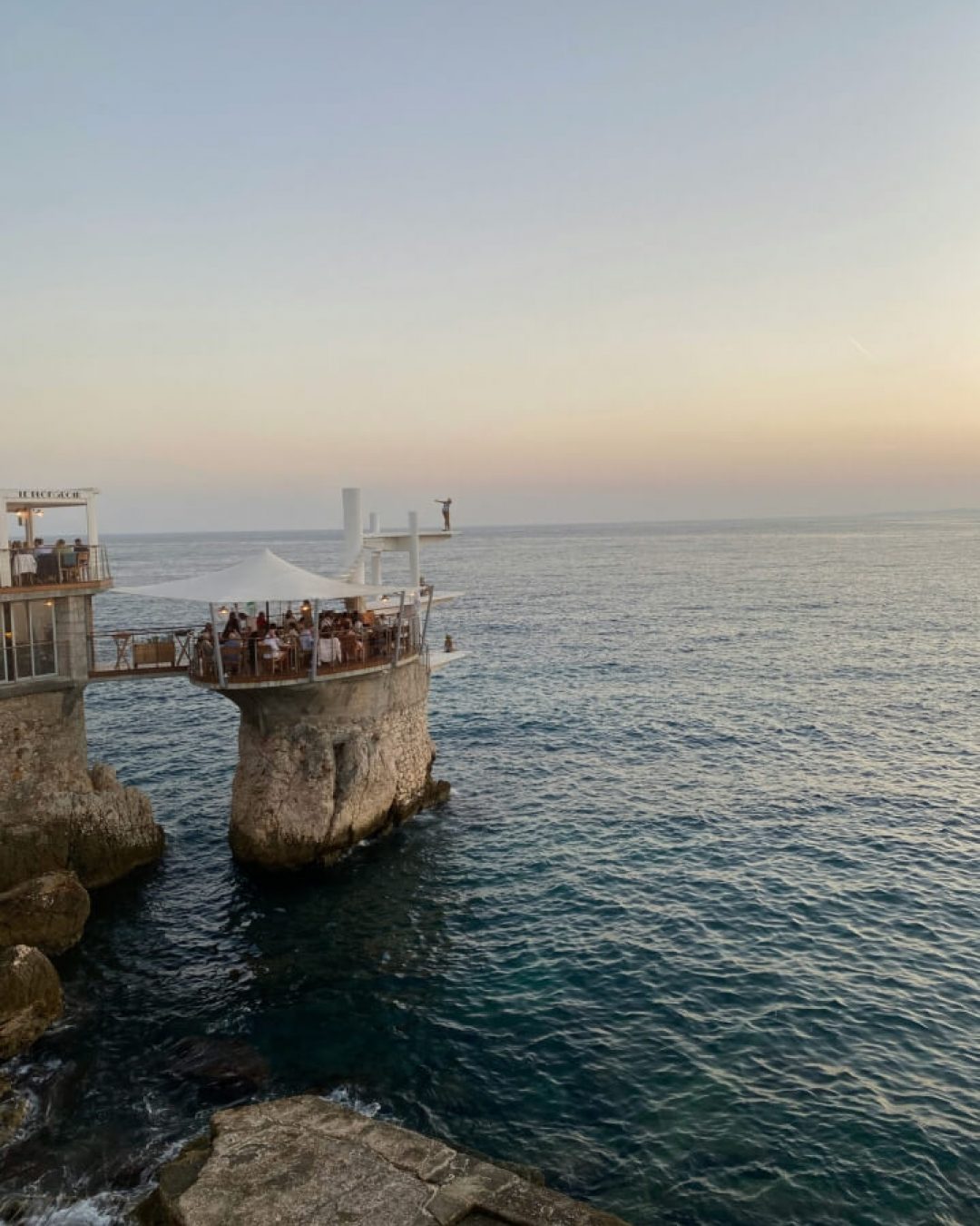 Romantic oceanside restaurant in Nice, France on natural cliffs along the Mediterranean coast.