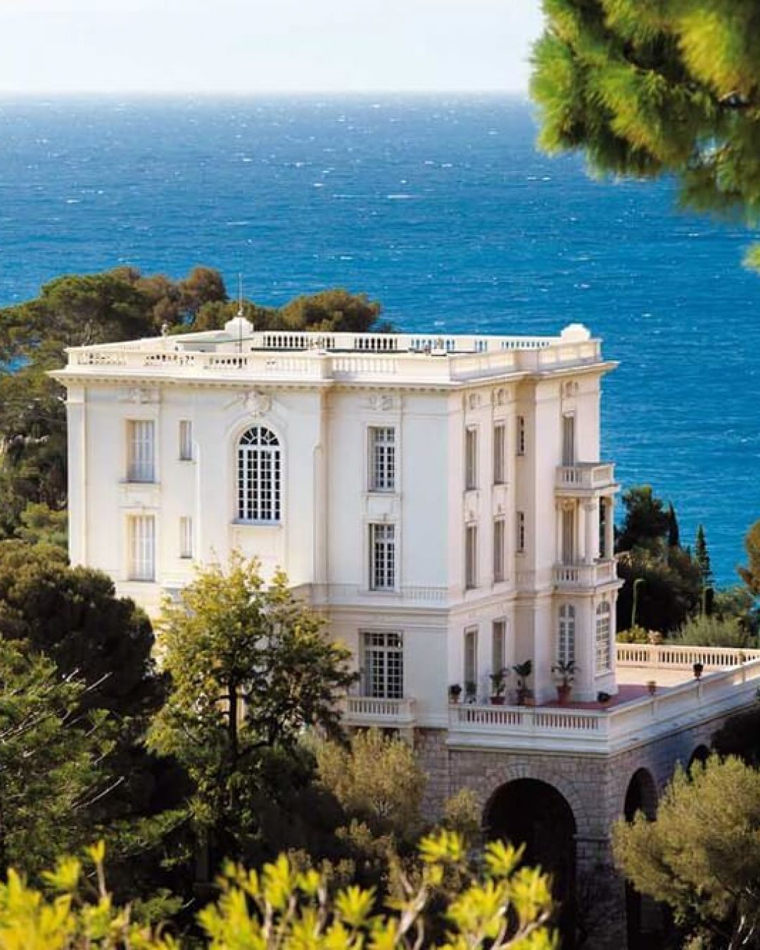 Karl Magerfeld's cliffside villa in Monaco, France beside lush greenery and the Mediterranean Sea.